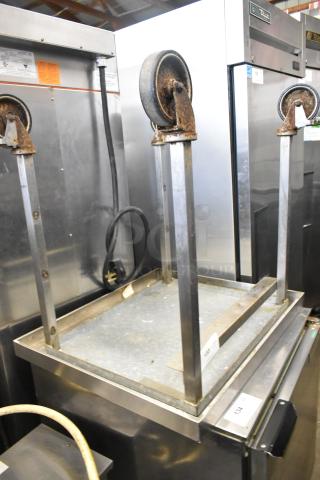 Stainless steel equipment stand with commercial casters, rust visible, designed for durability and mobility in industrial settings.