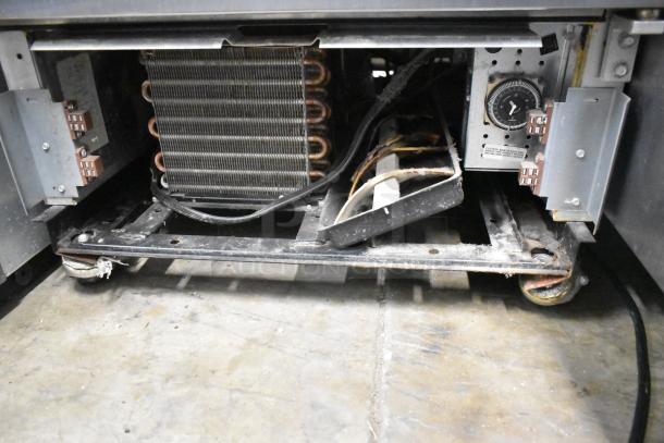 Interior condenser and components of 2016 True T-19F stainless steel commercial freezer, shown on caster wheels.