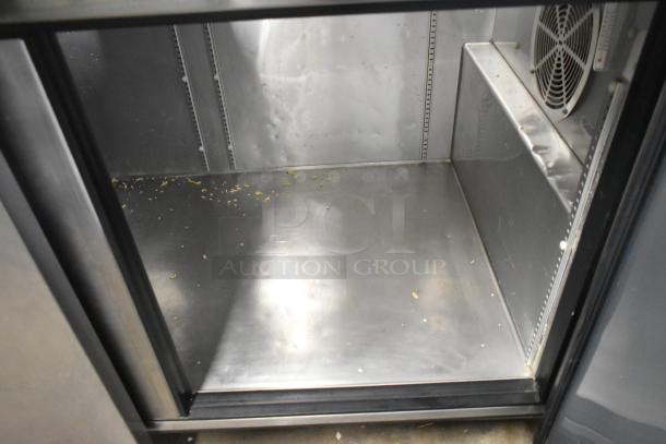 2017 True TPP-67 stainless steel commercial pizza prep table interior, showing minor debris and fan, on casters, 115V, 1 phase.
