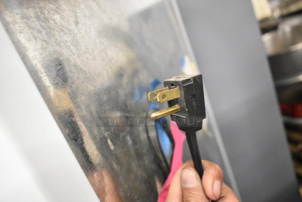 Power plug of a Maytag single door reach-in cooler with freezer, 115 volts, 1 phase. Black cord, standard plug.
