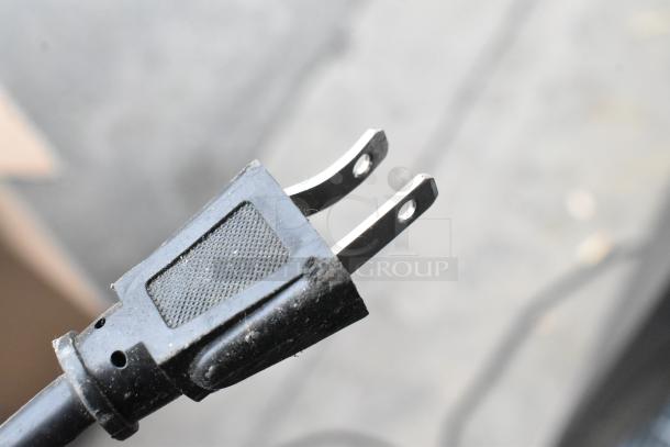 Close-up of a black two-prong electrical plug with a textured grip, showing slight wear.