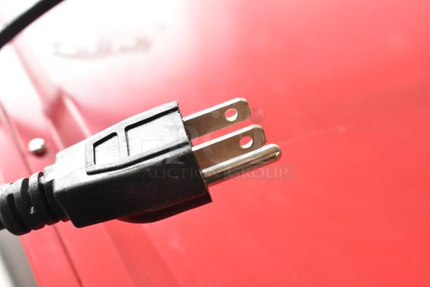 Close-up of Nostalgia CCP510 popcorn cart's power plug on red metal housing. Model designed for 120 volts, 1 phase.