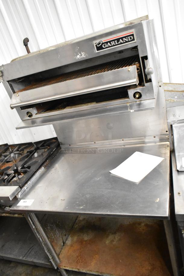 Garland Stainless Steel Gas Cheese Melter with table, backsplash, and undershelf. Visible Garland logo, clean condition.