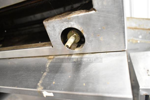 Garland stainless steel commercial gas cheese melter detail. Features include table, backsplash, and undershelf. Visible wear.