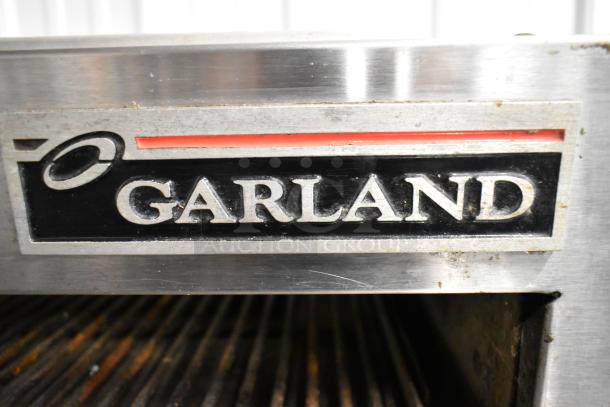 Garland stainless steel commercial gas cheese melter, features logo. Includes table, back splash, and under shelf.