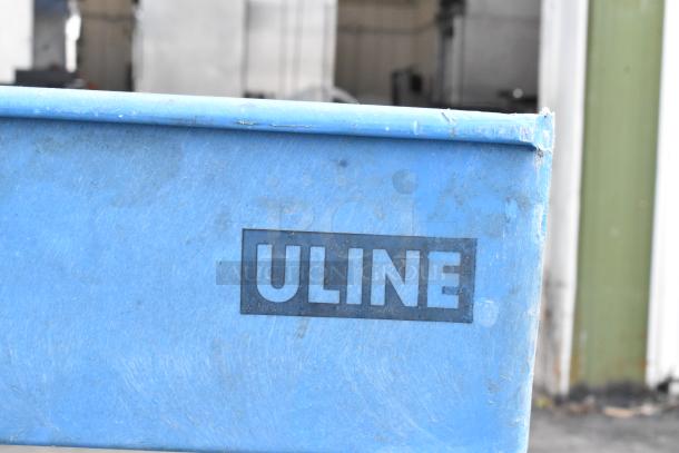 Blue two-tier ULINE poly cart with commercial casters, visible wear, ideal for industrial use.