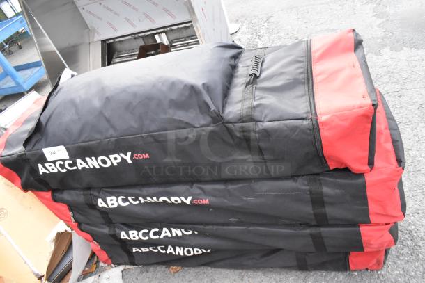 Four ABC Canopy pop up canopies in bags, black and red, with ABCCANOPY.com logo, sold as a lot.
