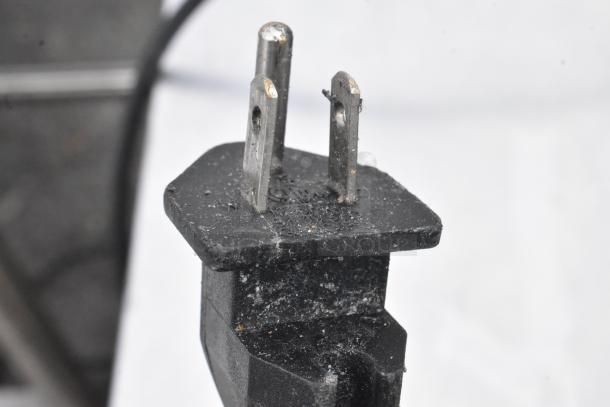 Close-up of a power plug from the B Air VP-50 air mover fan, showing a slightly worn three-prong design.