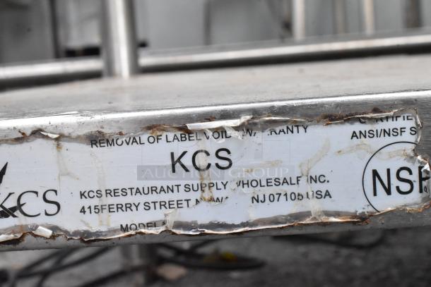 Stainless steel table with backsplash and under-shelf. Visible KCS Restaurant Supply label; some wear on edges. ANSI/NSF certified.