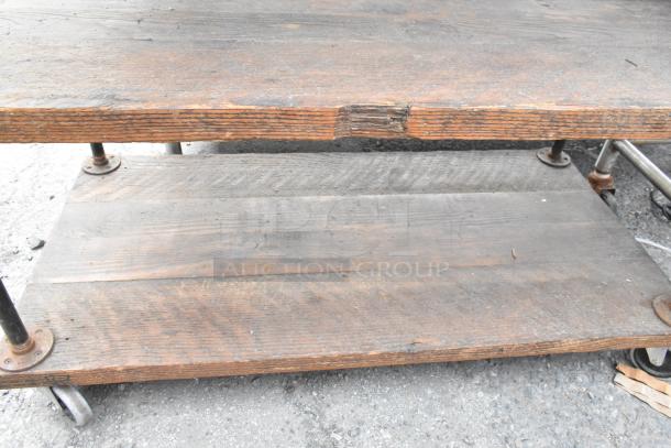 Wooden and metal 3 tier cart with commercial casters, visibly worn wood surfaces, sturdy metal support, ideal for industrial use.