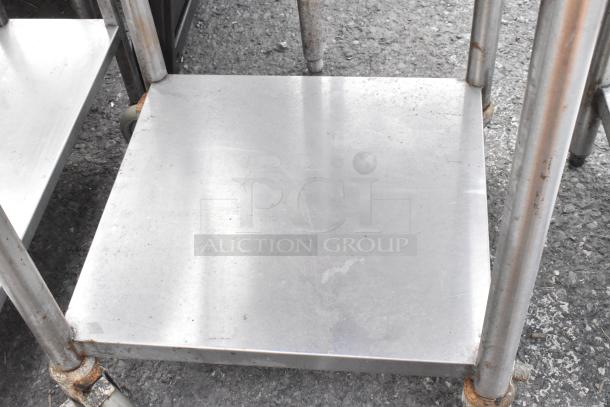 Stainless steel table with under shelf on commercial casters, showing signs of wear and rust on frame.