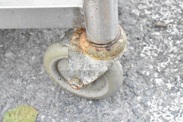 Stainless steel table caster detail, showing wear and rust on swivel bracket, indicating used condition.