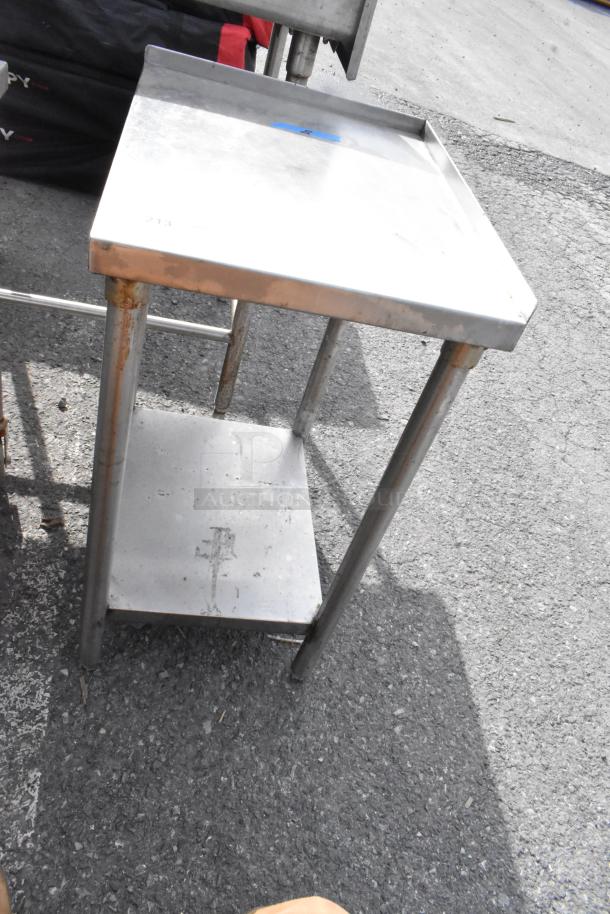 Stainless steel table with an under shelf, showing signs of rust on legs; used condition. Ideal for commercial use.