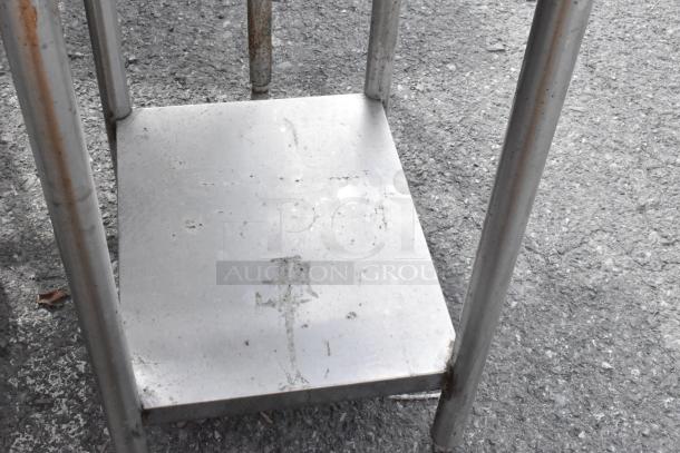 Stainless steel table with under shelf, showing signs of rust and wear. Suitable for industrial or kitchen use.