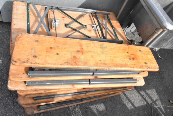 Stack of 16 wooden folding tables with metal legs, showing wear. Ideal for events or catering. Auction multiplies bid by 16.