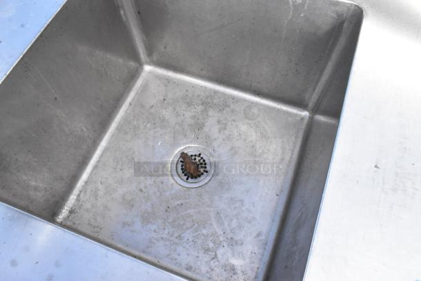 Stainless steel 2 bay sink with 2 faucets, showing visible wear and rust around the drain.