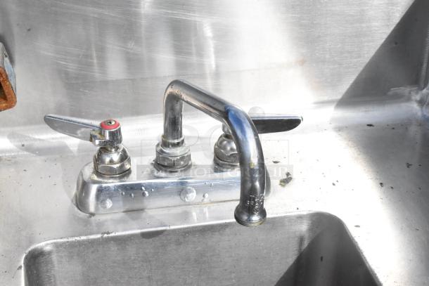 Stainless steel 2 bay sink with two metal faucets, showing some surface wear and few visible scuffs.