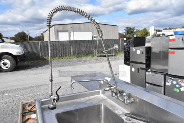 Stainless steel 2-bay sink with two faucets, including a high arc pre-rinse faucet, in good condition.