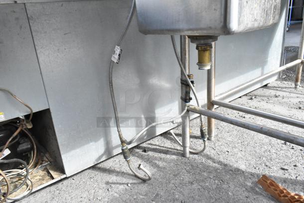 Stainless steel 2-bay sink with two faucets, visible plumbing, industrial setting, good condition, ID tag on hose.