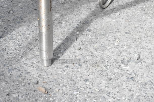 Stainless steel table leg with minor rust, sturdy condition, suitable for industrial use.