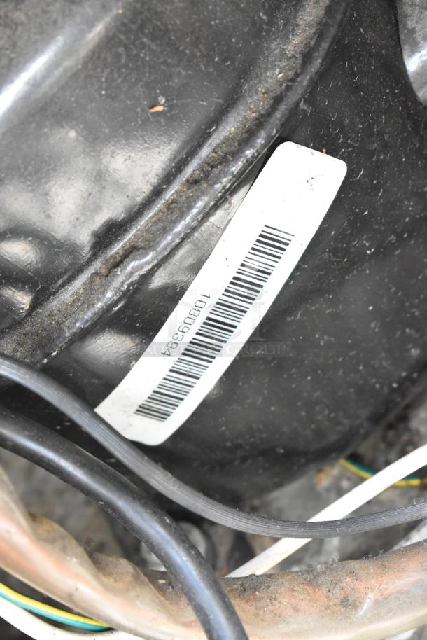 Barcode label on stainless steel commercial undercounter cooler, model 10890349, showing wiring and black cylindrical surface.