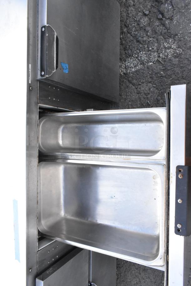 Stainless steel commercial cooler with 4 drawers, 1 door, and casters, 115 volts, 1 phase, in good condition.