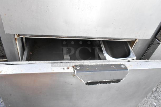 Stainless steel undercounter cooler with 4 drawers, 1 door, commercial casters, 115 volts, 1 phase; used condition, visible wear.