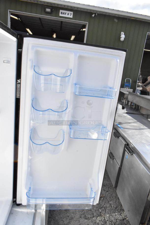 Open door view of a mini cooler with multiple clear plastic shelves. Auction for five coolers: Frigidaire, GE, Galanz.
