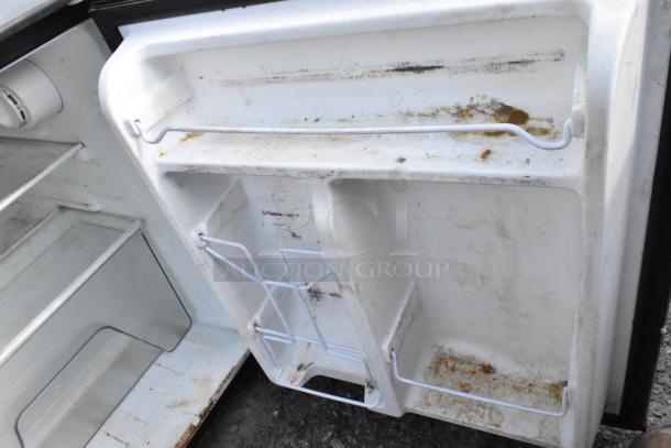 Interior of a used mini cooler showing shelves and door racks with visible wear and stains.