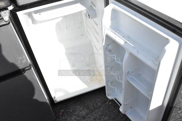 Open mini cooler interior with shelf racks visible. Sold in a lot of 6, including brands like Galanz and Whirlpool. Some signs of wear.