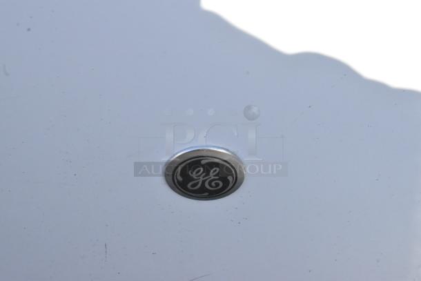 A GE logo on a white surface of a mini cooler, part of a lot including various models; condition is important for bidding.
