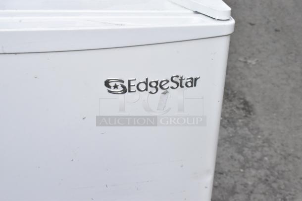 EdgeStar mini cooler, model CMF151L-1, visible logo, white exterior, shown on a rough surface, 115 volts.