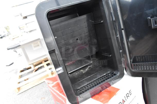 Frigidaire EFMIS183-SS Mini Cooler, open view, showing interior. Black finish, uses DC 12V/AC 120V. Slight wear evident.