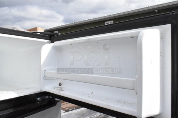 Open white freezer compartment of a mini cooler, showing some dirt and wear.