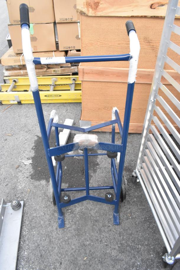Blue metal barrel dolly, brand new with minor scratches and dents, features black handles and rubber wheels.