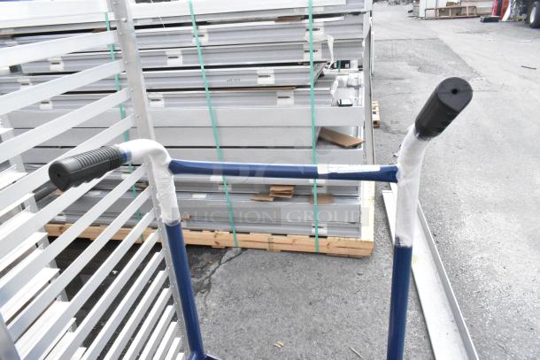 Blue metal barrel dolly, new with minor scratches and dents, sturdy handles, visible protective wrapping, auction item.