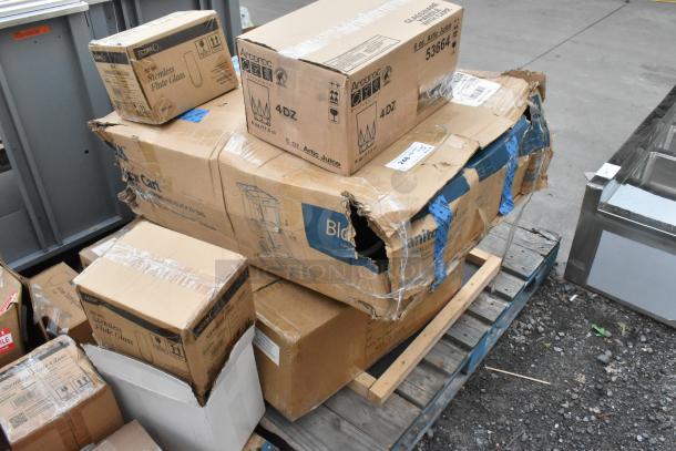 Damaged boxes containing new items like Acopa stemless flute glasses, ingredient bin, and Libbey coupe glasses on a pallet.