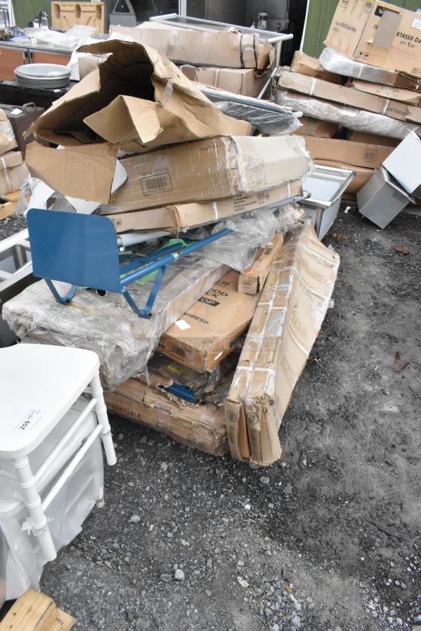 Pile of 18 new scratch and dent items, including Lancaster table bases, Lavex trucks, Regency work tables in damaged packaging.