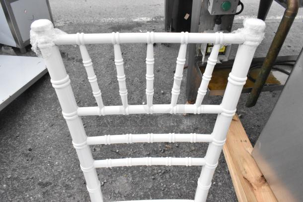 White Chiavari stackable banquet chair, new with scratch and dent marks, features protective wrap on corners.