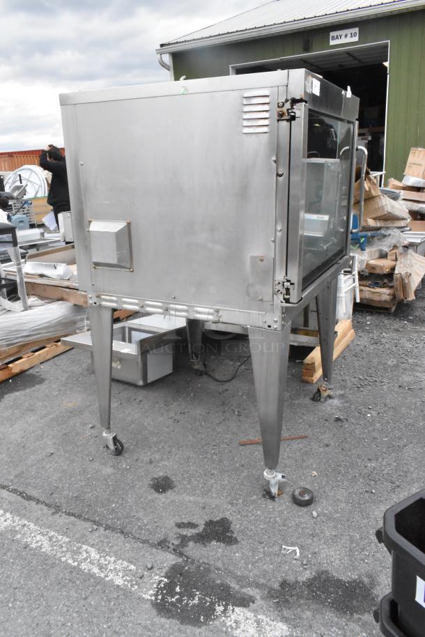 Hardt Inferno 4500 stainless steel rotisserie oven, natural gas powered, with skewers and metal legs on commercial casters.