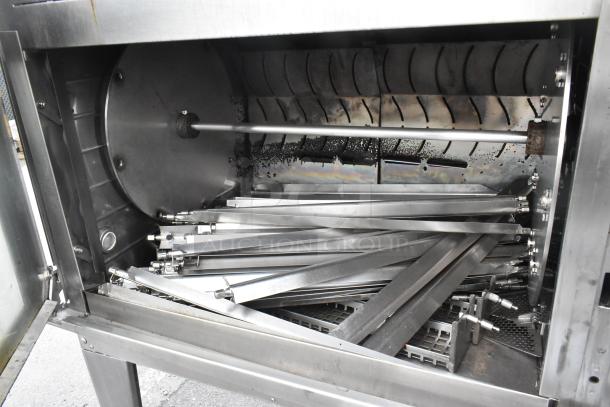 Hardt Inferno 4500 stainless steel rotisserie oven, natural gas powered, with skewers and metal legs on commercial casters.