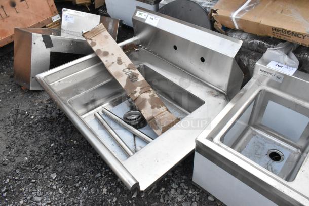 Brand new Regency 600DDT36L 16 Gauge 3' soiled dish table with left drainboard. Visible minor scratches. Tags show model and NSF logo.