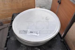 18 brand new metal round baking pans, scratch and dent condition, stacked, label shows auction lot details.