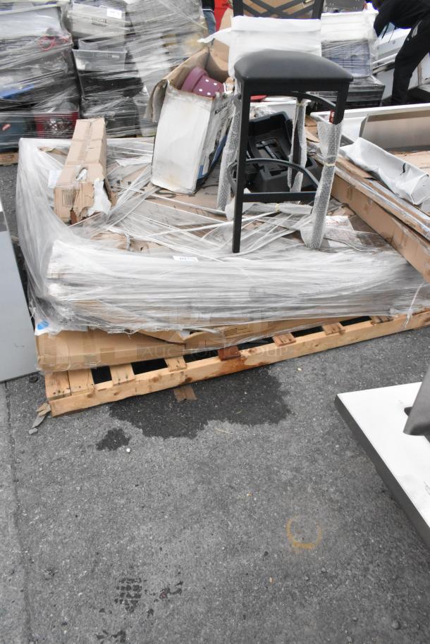 Pallet of assorted new scratch and dent items, including shelving, table bases, and a folding table, wrapped in plastic.