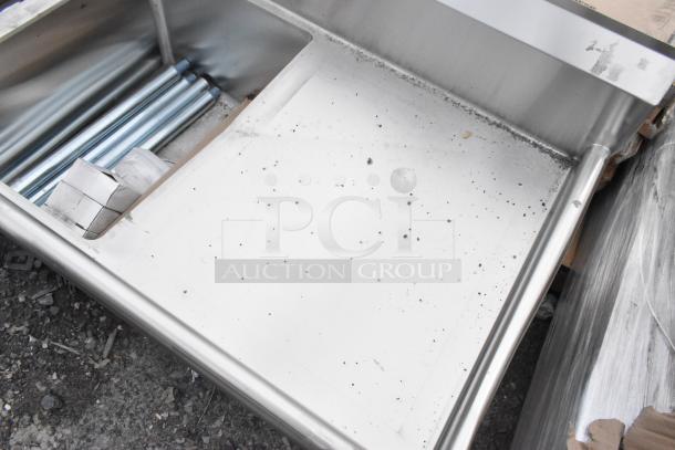 Brand new Regency 600S31824224 stainless steel 3-bay sink with dual drain boards, showing minor scratches and dents.