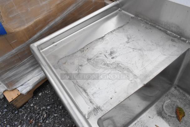 Brand new Regency 600S31824224 stainless steel 3 bay sink with scratches, dents, and dual drain boards visible.