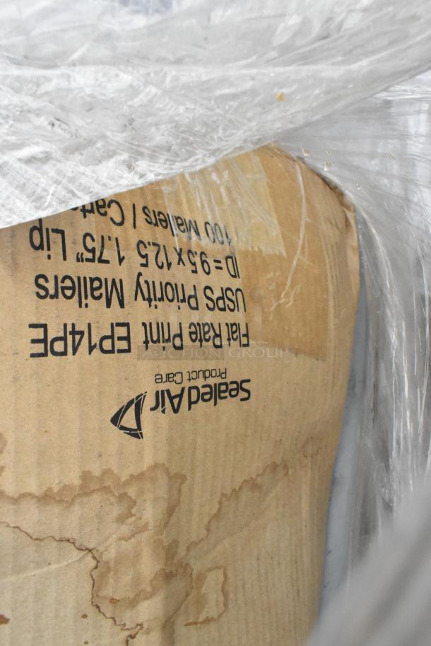 A sealed cardboard box with visible "Sealed Air" logo and dimensions, part of a lot including fry baskets and poly bins.