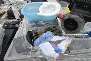 Lot of assorted items including a blue basin, white strainer, metal grid, plastic jug, and packaged textiles. Mixed condition.