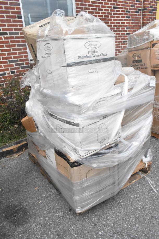 Stack of new scratch and dent items on a pallet, including Visions 18 oz. clear plastic stemless wine glasses in original packaging.