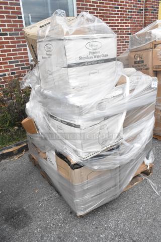 Stack of new scratch and dent items on a pallet, including Visions 18 oz. clear plastic stemless wine glasses in original packaging.